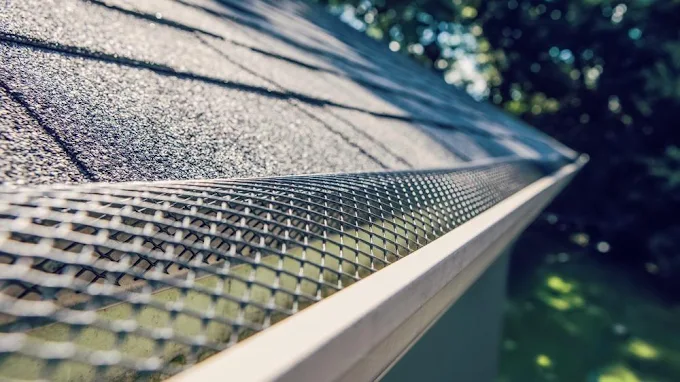 Close-up of a seamless aluminum gutter with leaf guard installed on a shingle roof